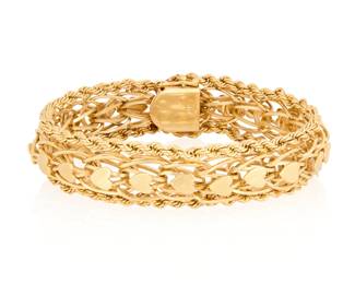 92 A 14K Gold Bracelet Of a fancy woven design featuring heart-shaped textured gold motifs  Measures: 7 1/4 in. 41.4 grams gross Estimate: $2,000 - $3,000