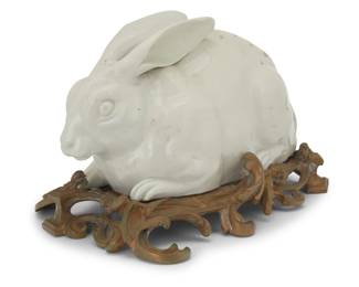 250 A Continental blanc de chine porcelain model of a rabbit Early 20th century Raised on a gilt-bronze stand Overall: 6.875" H x 11.5" W x 7.25" D Estimate: $800 - $1,200