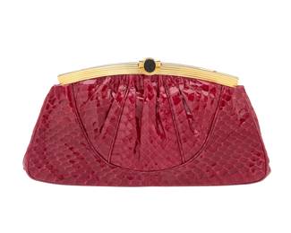 143 Judith Leiber: A Red Exotic Leather Clutch Bag Marked to interior plaque: Judith Leiber / © A vintage red snake leather purse with a gold-toned curved frame and a golden clasp featuring a black 'intaglio seal' with helmeted profile, with a drop-in chain strap and a tonal grosgrain lining, with one zip pocket  5 in. H x 9 1/4 in. W x 1 1/2 in. D; strap drop: 19 1/2 in. Estimate: $200 - $300
