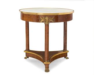 319 An Empire style gilt bronze mounted guéridon 20th century Surmounted by a circular marble top, raised on three columnar supports headed by anthemion and sphynx mounts, joined by an inswept undertier, on gilt bronze paw feet 30.5" H x 31" Dia. Estimate: $800 - $1,200