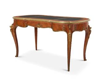 352 A Louis XV style bureau plat 20th century With gilt-bronze-mounted upper trim, foliate mounts, female figural accents, and foliate scroll sabots, with gilt-stamped black leather top above a single locking drawer 30" H x 55" W x 29.5" D Estimate: $1,500 - $2,000
