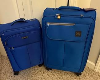 This set includes two blue soft-sided suitcases from The Skyway Luggage Co. The larger suitcase appears to be a checked-size bag, while the smaller one is likely a carry-on. Both feature a textured diamond-patterned fabric, telescoping handles, top and side carry handles, and spinner wheels for maneuverability. The larger bag has a front zippered pocket and a TSA-approved lock. The visible branding is a rectangular dark brown patch with the "The Skyway Luggage Co." logo in a stylized script and airplane graphic. Based on the historical sales data, this set is likely part of the Skyway Mirage 2.0 collection.