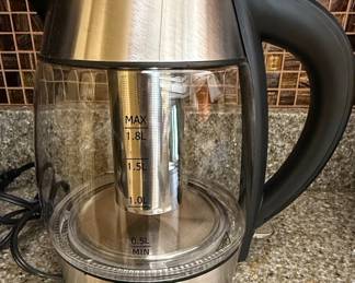 This Chefman electric glass kettle features a durable borosilicate glass body, allowing for clear visibility of the water level and brewing process. The kettle includes a removable stainless steel tea infuser basket, ideal for steeping loose leaf teas or herbal infusions. Its base is constructed from brushed stainless steel, providing a sleek and modern aesthetic. The handle is designed for a comfortable and secure grip, and the lid opens with a simple push button. Integrated measurement markings on the glass indicate water levels from 0.5L to 1.8L MAX. The kettle is designed for efficient and rapid boiling, with automatic shut-off for safety.