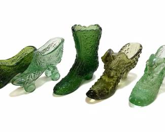 A collection of glass "Cinderella" slipper figurines, also known as "boot" or "shoe" vases, featuring the Daisy and Button pattern. These decorative items are often made from pressed glass and typically feature intricate patterns inspired by historical footwear. The Daisy and Button pattern, characterized by its geometric, textured design, is clearly visible on many of the pieces. They are commonly found in various colors, including the emerald green, amber, yellow, blue, and clear glass seen in the provided images. The design often includes a heel and a pointed toe, with an opening at the top suitable for holding small floral arrangements or serving as a standalone decorative piece. Their appeal lies in their whimsical design and the variety of colors and glassmaking techniques used, particularly the prominent Daisy and Button motif.