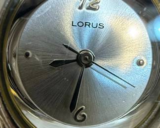 This lot contains two women's quartz wristwatches. The first is a Lorus watch with a silver-tone dial, silver-tone metal band, and a stainless steel caseback. It features a simple dial with hour markers and Arabic numerals at 12 and 6 o'clock. The second is a Milan watch with a champagne-colored dial, gold-tone bezel, and a two-tone metal band. It is marked as 'DIAMOND QUARTZ' and has a stainless steel back with a base metal bezel. Both watches appear to be functional quartz movements, suitable for everyday wear.