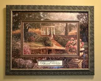 This framed artwork, titled "Spring Promise" by Christian World Inc., features a serene landscape scene with a classical gazebo and abundant floral elements. A prominent matting highlights a central inscription of Psalm 84:5, "Blessed are those in whom you live." The artwork is housed in an ornate, multi-layered frame with a distressed metallic finish and decorative detailing. A manufacturer's label on the back identifies it as AP723, with a product code of 102699 and SPN# 5511970050. The piece appears to be mass-produced, likely intended for home decor with a religious theme. The overall style evokes a traditional or romantic landscape aesthetic.