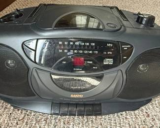 This Sanyo MCD-Z101 is a portable boombox-style stereo system that combines a CD player, AM/FM radio tuner, and a cassette recorder. It features built-in stereo speakers, a digital display for the CD player, and a prominent tuning dial. The unit is powered by AC adapter or 8 D-cell batteries, making it suitable for both home and portable use. The design is typical of portable audio devices from the late 1990s, prioritizing functionality and versatility.