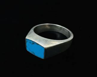 This is a men's sterling silver signet ring featuring a rectangular inlay of natural turquoise. The silver has a brushed finish, giving it a slightly matte appearance. The turquoise stone is a vibrant blue with characteristic matrix webbing, set flush within the silver band. The ring has a substantial feel, indicative of a well-crafted piece. The shank is smooth and tapers slightly towards the back. The ring features a maker's mark that appears to be 'MEX S' with a number '0-315' below it, suggesting Mexican origin and craftsmanship. The overall style suggests a mid-20th century to contemporary Southwestern or Native American influence.