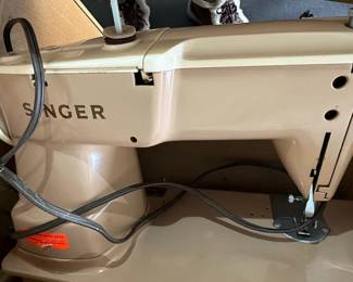 This listing features a vintage Singer 403A Slant-O-Matic sewing machine, presented in a classic beige and cream color scheme. The machine exhibits the characteristic design of mid-20th-century Singer models, known for their durability and functionality. Accompanying the sewing machine is its original Singer Sewing Motor Controller foot pedal, also in a dark brown plastic casing. The foot pedal is marked with 'Singer Sewing Motor Controller,' 'Volts 95-145,' 'Amperes 0.7,' and 'Part No. 197629,' indicating it is designed for a specific range of electrical input and manufactured by The Singer Mfg. Co. in Elizabethport, New Jersey. The overall aesthetic suggests a functional piece of vintage machinery, likely from the 1950s or 1960s, suitable for collectors or those seeking a working vintage sewing machine.
