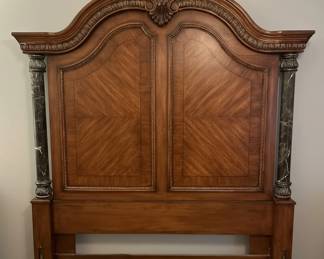 This grand queen size headboard embodies the opulence of Italian Neoclassical design, featuring a rich mahogany wood frame with intricate detailing. The central panel showcases a striking sunburst veneer pattern, meticulously arranged to create depth and visual interest. Flanking the central section are two substantial columns, clad in dark, veined marble, adding a touch of classical gravitas. The overall aesthetic is one of refined elegance, characterized by its symmetrical composition, decorative moldings, and the harmonious blend of wood and stone. This piece would serve as a majestic focal point for a master bedroom, evoking a sense of historical grandeur and sophisticated luxury.