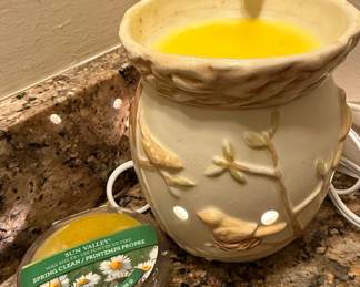 This lot includes a Scentsy "Nature's Haven" wax warmer, model DSW-NATR, and a "Spring Clean" wax melt from the Sun Valley line. The ceramic warmer is cream-colored and features a decorative motif of birds and branches with cut-out sections for light emission. It operates on a 120V, 60Hz, 25W power supply and is for household use only. The accompanying 2.4 oz (69g) wax melt is in the "Spring Clean" scent, described as a fresh, floral, and herbaceous fragrance with notes of white florals, green leaves, and a hint of citrus. The "Nature's Haven" warmer is a retired and sought-after model.