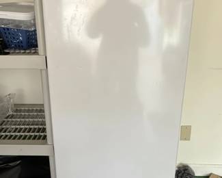 This is a white Magic Chef upright freezer, model HMUF6WE, with a capacity of 5.8 cu. ft. It is designed for home use and features a reversible door and adjustable temperature control. The interior is equipped with wire shelving for organization. The exterior shows some signs of wear and dust, suggesting it is a used appliance. The brand logo, 'Magic Chef', is prominently displayed on the front. A similar model, the HMUF6WE, is listed for sale.