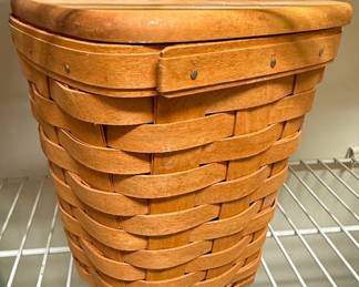 This is a handwoven Longaberger basket, identified as the "DAR" Collector's Edition from 1995. The basket is crafted from wood splints, likely maple or ash, with a natural finish. It features a hinged lid with a wooden knob and is constructed using traditional basket-weaving techniques, secured with small nails. The base of the basket is marked with "LONGABERGER BASKETS HANDWOVEN DRESDEN, OHIO USA" and handwritten "DAR 1995". This particular edition was often part of a series released by Longaberger, celebrating specific themes or organizations.