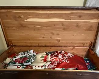 This is a vintage cedar-lined blanket chest, likely dating from the mid-20th century, manufactured by the Lane Company. The exterior is constructed from dark stained wood, possibly walnut, featuring a curved lid and decorative carved or applied molding around the base and an oval motif on the front panel. The interior is lined with aromatic cedar wood, a traditional material for protecting textiles from moths and moisture. The chest has a lock mechanism and is supported by short, carved feet. Its design suggests a piece of functional furniture that also served as a repository for personal belongings. Many Lane cedar chests from this era feature a "Style" number and manufacturing date stamped inside, which can help to further refine the identification.