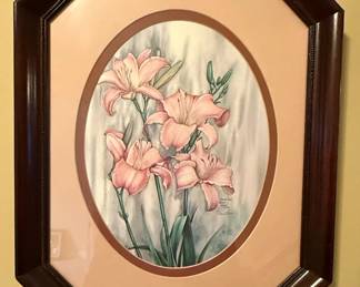 This is a limited edition print by artist Carmel Foret, titled "Pink Daylilies." The artwork depicts a cluster of delicate pink daylilies with green stems and leaves against a softly blended background. The print is signed by the artist and numbered 454 out of an edition of 1800, with the copyright year noted as 1986. It is presented in an octagonal, dark wood frame with a complementary pale peach matting around the oval image. The overall aesthetic is floral and serene, characteristic of decorative art from the late 20th century.