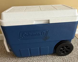 This is a Coleman 50-quart Xtreme 5-Day wheeled cooler, designed for portability and durability. It features a robust blue and white plastic construction with a textured lid and body. The integrated wheels and telescoping handle facilitate easy transport, making it ideal for camping, tailgating, and other outdoor activities. The cooler's primary function is to maintain temperature for extended periods, preserving food and beverages. The 'Xtreme 5-Day' designation indicates advanced insulation technology for extended cooling.