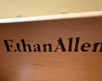 This is a substantial and elegant Ethan Allen French Country tall open bookcase with an integrated set of three drawers. The upper section features adjustable shelves within an arched top cabinet, providing ample display and storage space for books and decorative items. The lower section comprises three drawers, each with decorative brass-toned hardware, offering concealed storage. The overall construction appears to be solid wood with a rich, warm wood finish, likely cherry or mahogany, indicative of Ethan Allen's commitment to quality and traditional design. The piece exhibits classic lines and would complement a variety of interior styles, from traditional to transitional.