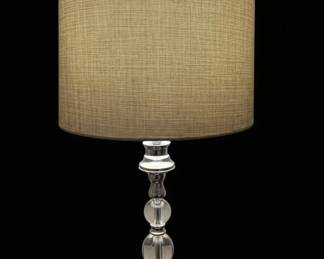 This table lamp features a drum-shaped shade crafted from a textured, neutral-toned fabric, likely linen or a synthetic blend, with a dark trim. The base is constructed from polished metal, possibly chrome or stainless steel, and showcases a decorative column with stacked spherical elements, some appearing to be clear acrylic or glass, interspersed with metal accents. The overall design suggests a contemporary or transitional style, suitable for various interior decors. The lamp is powered by a standard electrical cord and plug, and a UL certification sticker indicates it meets safety standards for electrical products in North America. The manufacturing label indicates it was made in China in October 2015 by Bright Lighting Co., Ltd., with the item/article number ITM./ART: 678173.