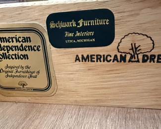 This American Drew sideboard, part of the "American Independence Collection," is crafted from rich, dark wood, likely mahogany or a high-quality veneer, showcasing a traditional style. It features a central drawer with ornate brass hardware, flanked by two cabinet doors with inset panels that exhibit subtle wood grain patterns. The base has a decorative, stepped plinth, and the overall construction suggests a durable and elegant piece of furniture. The "American Independence Collection" line is inspired by the original furnishings of Independence Hall, aiming to capture a sense of historical significance and classic American design. The brass hardware, with its intricate scrollwork, complements the dark wood finish, creating a piece that is both functional and decorative.