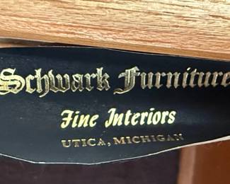 This is a large, traditional china cabinet manufactured by Schwanek Furniture, a company known for its "Fine Interiors" line. The cabinet is constructed from dark-stained wood, likely mahogany or cherry, with a rich, warm finish. It features a multi-paneled glass upper section with decorative mullions forming an intricate diamond pattern, designed to display china and decorative items. The lower section comprises several drawers and cabinets, offering ample storage. The hardware appears to be ornate brass, consistent with traditional furniture styles. The overall aesthetic suggests a piece from the mid to late 20th century, designed to be a focal point in a dining room or living area.