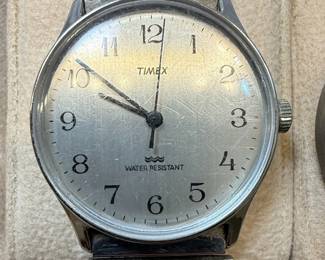 This lot features two distinct wristwatches. The first is a Timex watch with a silver-tone dial, Arabic numerals, and 'WATER RESISTANT' marking. It has a metal expansion band and a base metal bezel with a stainless steel back, assembled in the Philippines. The second is a Bijou Terner quartz watch with a white dial, featuring a Swiss cross emblem at the 12 o'clock position, Arabic numerals, and 24-hour markings. It is marked 'JAPAN MOVT' and 'STAINLESS STEEL BACK'. Both watches show signs of wear consistent with age and use.