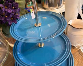 The Le Creuset 3-Tier Stand in Marseille blue is a versatile, 14.5-inch tall, high-quality stoneware serving piece designed for displaying desserts, appetizers, or fruit.
