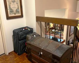 A couple of pieces of new luggage sit next to a much larger, older trunk.