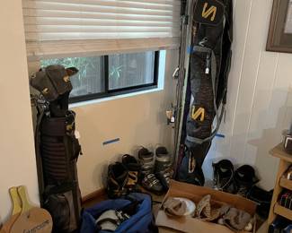 There are skis, ski boots, golf clubs, smashball paddles, and baseball/softball gloves featured in this picture.