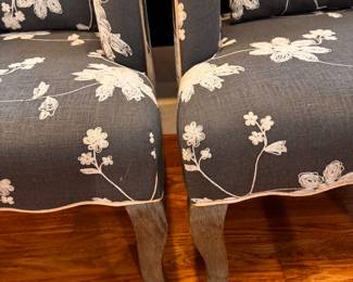 Two matching upholstered blue gray side chairs with white piping measure 27 inches wide by 35 inches tall by 27 inches deep. And beautiful shape and these are nice statement pieces.