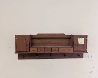 C166 - $30. Hanging Wall Shelf. Measures 38.5" wide x 6.5" deep x 14" tall. Has pegs to hang jackets and small drawers / doors for storage. 