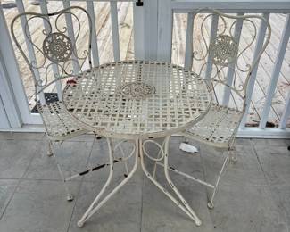 C76 - $40. Vintage Style White Wrought Iron Bistro Set that folds. Includes a round table and two matching chairs. Table is 24" x 26.25" tall. Chairs are 15.5" wide x 14" deep x 34" tall. Floor to seat is 17.25" Tall. 