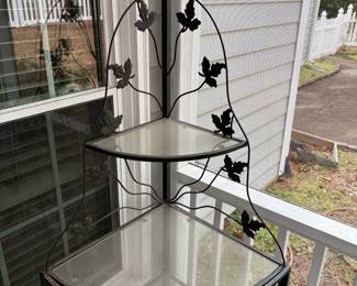 C74 - $65. Vintage Corner 4 Tier Metal Plant Stand with Glass Shelves and Ivy Leaf Accents. Magnetic doors on the bottom do not stick (easy repair) and some chipping paint. Has been used on screened in porch. Measures 29" wide x 20.5" deep x 64" tall. 