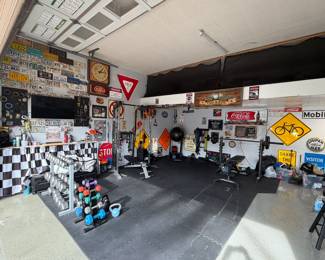Garage features a home gym with free weights and machines, as well as license plates and street signs