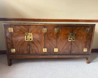 Vintage Walnut Sideboard Dynasty Collection by Drexel Heritage. The sideboard has two set of double doors that have brass hardware that mimics chinoiserie and campaign styling from the 1970’s. The doors open to reveal inner shelving on the left side and three drawers of staggering width on the right side. It is in good condition for its age with visible wear consistent with use. Can be buffed out. Made in the USA. (60” W x 19” D 30.5” H) $650