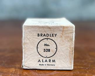 This lot features a vintage Bradley mechanical travel alarm clock, manufactured in Germany and is in good working condition.