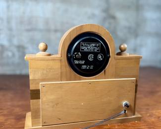 This lot features a vintage United Clock Corp. electric fireplace mantle clock, likely from the 1940s or 1950s in good working condition. This clock has a wooden case with white floral decorative accents on the uprights and a simulated log fireplace scene. 