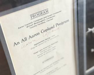 This lot features a professionally framed program signed by composer, Aaron Copland. Measures in frame, 15” H x 17.5” W.