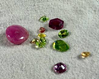 This lot features a collection of semi-precious gemstones including an earth mined sapphire, an earth mined ruby, and many others.