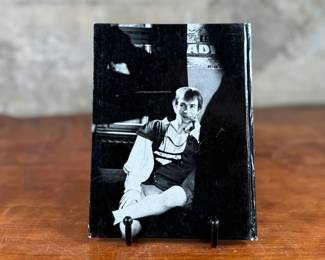 This lot features a rare, pocket-sized collectible book titled “RUDOLF NUREJEW” by German ballet critic Klaus Geitel. The book focuses on the famous ballet dancer Rudolf Nureyev at the height of his career and is signed on the front by Nureyev himself. The book is published by Rembrandt Verlag and comes in good overall condition.