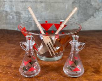 This lot features a rare mid-century Gay Fad "Moon" pattern set circa 1950s featuring atomic-style red and gold triangles and dots. The set includes a clear glass serving bowl, matching wooden serving utensils, and two glass cruets with stoppers. One of the stoppers has damage as shown in photos.