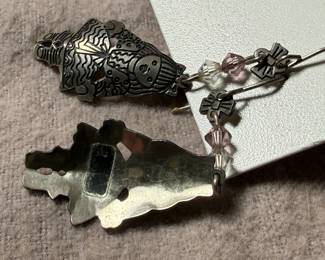 This lot features a pair of earrings by designer, Edgar Berebi. Edgar Berebi jewelry (1979–2001) is a highly collectible, American-made line known for intricate, limited-edition designs featuring 24K gold or silver plating, guilloché enamel, and Swarovski crystals. A Pratt Institute graduate, Berebi’s work often features detailed, artistic motifs ranging from Egyptian revival to whimsical animals and Christmas themes, commonly found as signed earrings, pins, and brooches.