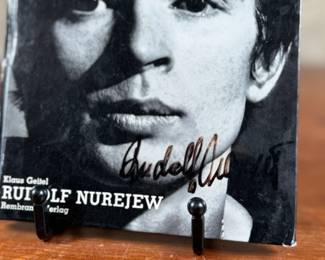 This lot features a rare, pocket-sized collectible book titled “RUDOLF NUREJEW” by German ballet critic Klaus Geitel. The book focuses on the famous ballet dancer Rudolf Nureyev at the height of his career and is signed on the front by Nureyev himself. The book is published by Rembrandt Verlag and comes in good overall condition.