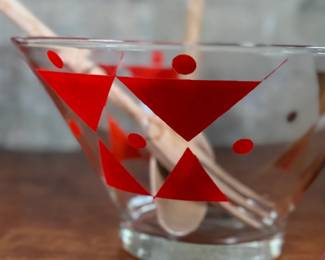 This lot features a rare mid-century Gay Fad "Moon" pattern set circa 1950s featuring atomic-style red and gold triangles and dots. The set includes a clear glass serving bowl, matching wooden serving utensils, and two glass cruets with stoppers. One of the stoppers has damage as shown in photos.