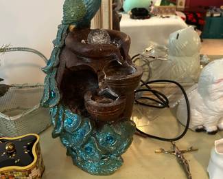 eacock and urn statue fountain is likely a table-top model made from poly resin with built-in LED lighting and a pump for cascading water. 
