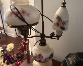 This item is a vintage-style hurricane table lamp, featuring a white glass base and shade with hand-painted pink floral designs. 
