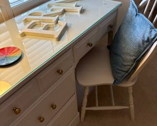 White desk with 4 drawers and chair. Desk has a glass protective top