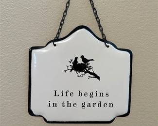 Another view of the small decorative white metal garden sign with the quote "Life begins in the garden" and a bird illustration