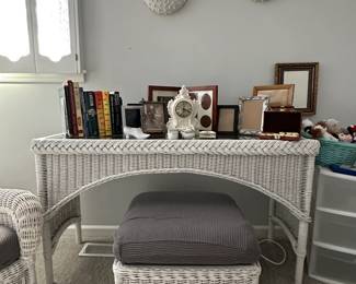 A white wicker side table and ottoman, with grey cushion