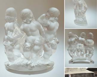 A signed Lalique France "Luxembourg" crystal figurine featuring three frosted cherubs, also known as putti, holding garlands.