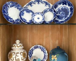 Antique English flow blue transferware china dishes, saucers, and platter; a vintage white and gold ceramic or porcelain lidded urn or temple jar featuring a chinoiserie floral design, a 1940s-50s Roseville Pottery Zephyr Lily Bermuda Blue cookie jar with lid and matching pair of candlesticks 